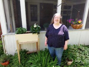 view of raised bed, wind chimes and hanging basket