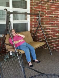 Sarah sitting on a swing in her sunroom