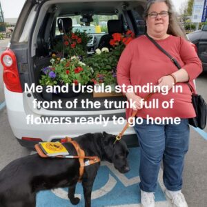 Sarah standing at the back of a car, trunk open to show it is full of plants