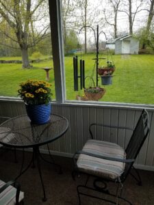 a small round table with flowers on it beside a window